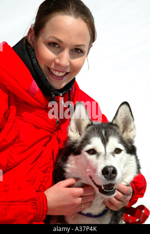 Frau Im Winter Mit Hund, junge Frau in rot Ski Kleid mit einem Hund Husky im Schnee Stockfoto