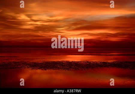 Die Sonne in einem feurigen goldene Dämmerung Licht über Wasser bei Ebbe. Stockfoto