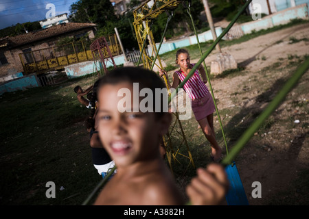 Jungen und Mädchen spielen auf einer Schaukel auf einem Spielplatz in Trinidad Stockfoto