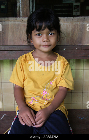 Junges Mädchen saß auf dem Balkon von ihrem Langhaus an den Ufern des Sungai Terika, Sarawak, Borneo, Malaysia Stockfoto