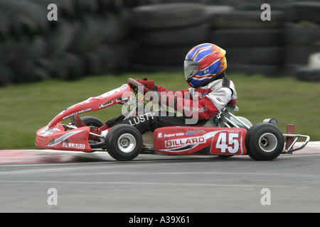 Junior Jnr Rotax max Kartfahrer verwischt über eine Kante mit Tyrewall im Hintergrund Nutts Ecke Motorsport Circuit Stockfoto