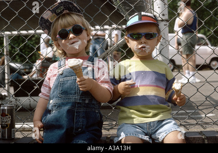 zwei junge Kinder essen Eis – Cream Cones in der Sonne Stockfoto