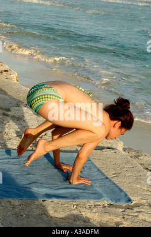 Crow stellen Kakasana Bakasana jungen Weibchen üben Yoga Asanas auf dem Sandstein Felsen in der Nähe von Meer Stockfoto