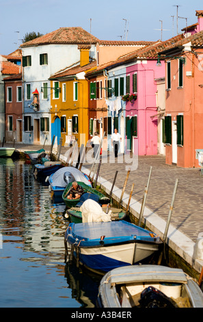 Italien Venetien Venedig Lagune Burano Insel bunten Häuser neben Kanal mit Booten vertäut in Wasserstraße und Passanten vorbei Stockfoto