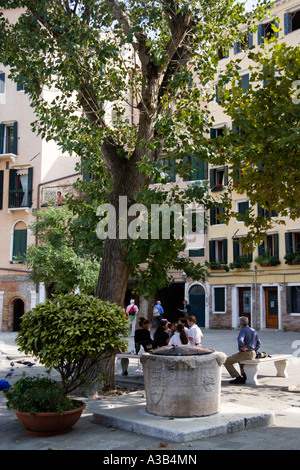 Italien Venetien Venedig Novo Gheto jüdische neue Ghetto Erwachsene und Kinder sitzen unter einem Baum neben einem capped Wasser gut auf Platz Stockfoto