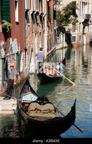 Italien Venetien Venedig Gondel mit Touristen vorbei an Kanal im Stadtteil San Marco mit einem anderen Gondoliere durch Schritte stehen Stockfoto