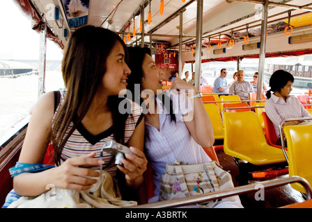 Zwei junge Thai-Frauen haben einen Tagesausflug auf einem Wassertaxi am Fluss Chao Phyra in Bangkok, Thailand Stockfoto