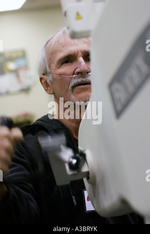 Älterer Mann mit Hilfe einer Sauerstoffmaske wegen seine Lungenkrankheit bei einem lokalen Fitnessstudio ausüben kann. Stockfoto