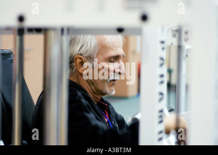 Älterer Mann mit Hilfe einer Sauerstoffmaske wegen seine Lungenkrankheit bei einem lokalen Fitnessstudio ausüben kann. Stockfoto