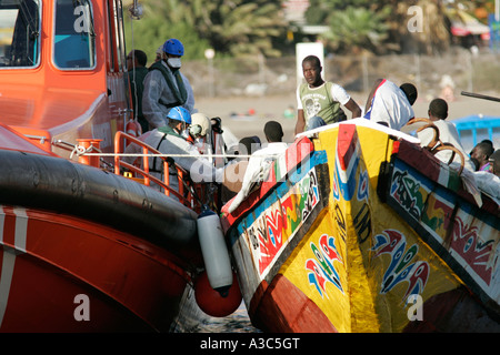 spanische Polizei und Beamte in Schutzkleidung und Masken Auf orange maritimo salvamento Boot entfernen illegale Einwanderer afrikanische Migranten Stockfoto