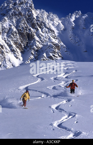 Frauen mit Snowboard und Männer mit Ski in tiefen Pouder Schnee Stockfoto