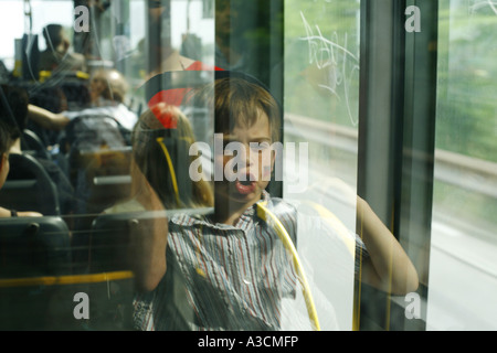 Kind in einem Busfenster spiegeln die deutsche Flagge gemalt auf die Wange, Deutschland, Berlin Stockfoto