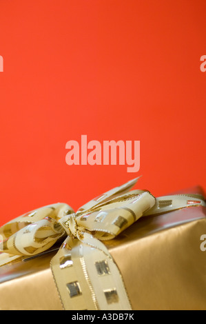 Vertikale Aufnahme des goldenen Geschenkkarton auf rotem Grund Stockfoto