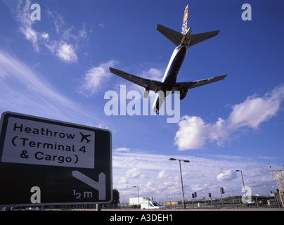 London Heathrow Flughafen Perimeter Straße mit Schild, Verkehr zu terminal 4 und Ladeflächen & Flugzeug absteigend zur Piste Stockfoto