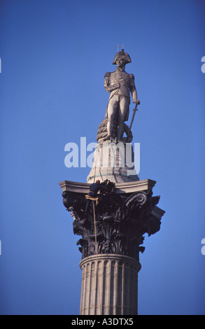 Ein Mann auf einer Docking-Station Reinigung Nelsonsäule knapp unterhalb der Statue von Lord Nelson, Trafalgar Square, London, England Stockfoto