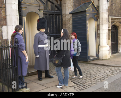 Mädchen necken eine königliche Wache im Dienst am St James s Palace Haupteingang London Stockfoto