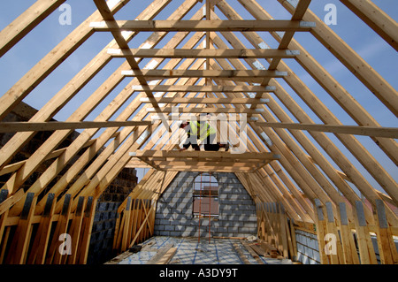 Ein Baumeister Vermessung der Dachstuhl eines neuen Hauses im Bau. Stockfoto