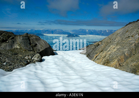 Weiten Blick über ein Schneefeld durch Felsen, Eisberge im Sermilik Fjord Eastgreenland Stockfoto