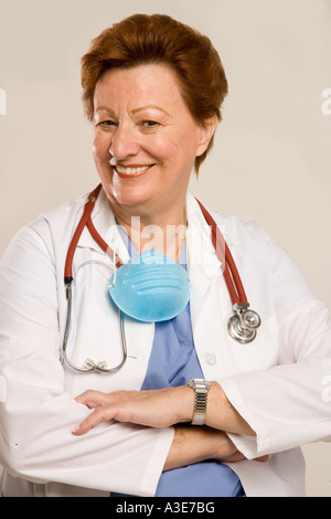 Ärztin mit Lab Mantel, Maske und Stethoskop lächelt. Stockfoto