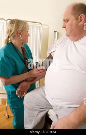 Krankenschwester Kontrollen übergewichtigen Patienten Blutdruck zum Jahresbeginn eine Wellness-Prüfung. Stockfoto