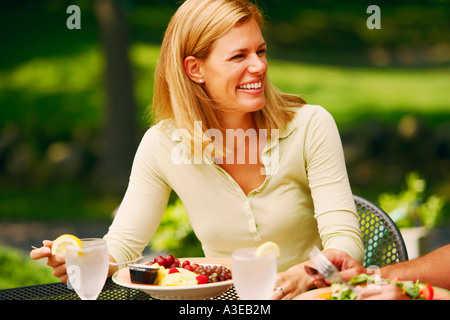 Nahaufnahme einer Mitte erwachsenen Frau sitzt an einem Tisch mit einem Teller Salat vor ihr Stockfoto