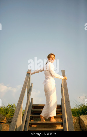 Niedrigen Winkel Blick auf eine reife Frau, stehend auf einer Treppe Stockfoto