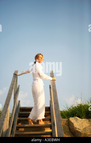 Niedrigen Winkel Blick auf eine reife Frau, stehend auf einer Treppe Stockfoto