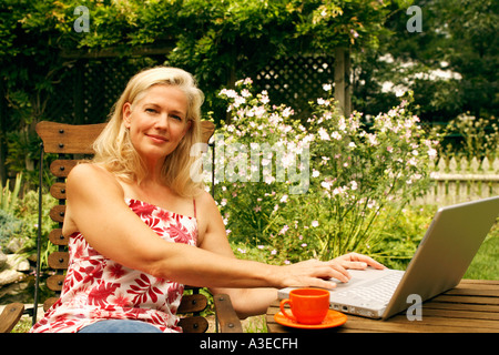 Porträt einer reifen Frau auf einem Stuhl sitzend und mit einem laptop Stockfoto