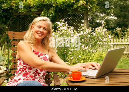 Porträt einer reifen Frau auf einem Stuhl sitzend und mit einem laptop Stockfoto