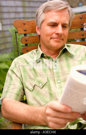 Nahaufnahme von einem reifen Mann auf einem Stuhl sitzen und ein Buch zu lesen Stockfoto