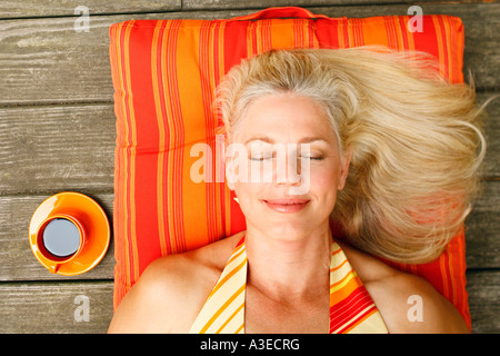 Vogelperspektive Blick auf eine reife Frau mit geschlossenen Augen auf dem Rücken liegend Stockfoto