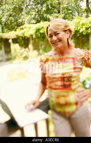 Porträt einer reifen Frau, die mit einem Laptop mit der Hand auf ihre Hüfte Stockfoto