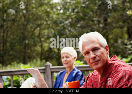 Porträt von einem reifen Mann hält eine Tasse mit einer älteren Frau im Hintergrund Stockfoto