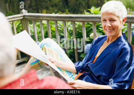 Nahaufnahme einer senior Frau hält eine Zeitung und Blick auf einen Reifen Mann Stockfoto