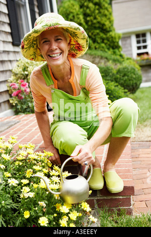 Portrait einer älteren Frau Bewässerung von Pflanzen und lächelnd Stockfoto