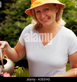 Porträt einer reifen Frau Bewässerung von Pflanzen und lächelnd Stockfoto