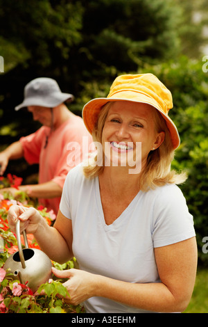 Porträt einer reifen Frau Bewässerung von Pflanzen und lächelnd Stockfoto
