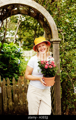 Porträt einer reifen Frau hält eine Topfpflanze und lächelnd Stockfoto
