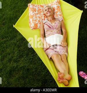 Erhöhte Ansicht einer älteren Frau ein Buch hält und liegen in der Hängematte Stockfoto