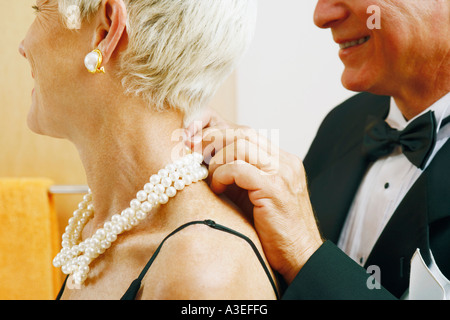 Nahaufnahme eines reifen Mannes setzen eine Perlenkette um eine reife Frau Hals Stockfoto