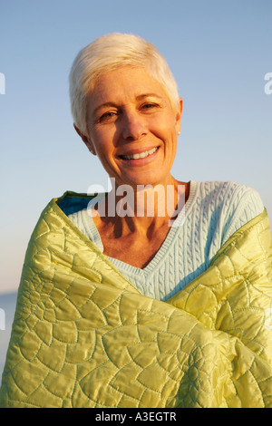 Porträt einer reifen Frau in eine Decke gehüllt und lächelnd Stockfoto