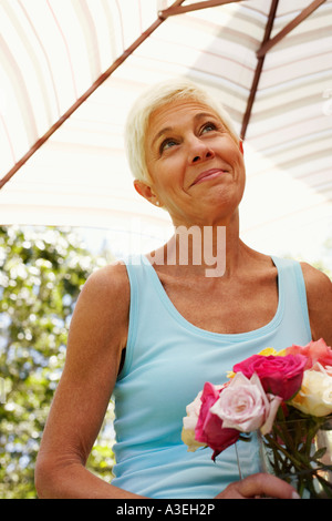 Nahaufnahme einer reifen Frau hält Blumen in einer Vase und nachschlagen Stockfoto