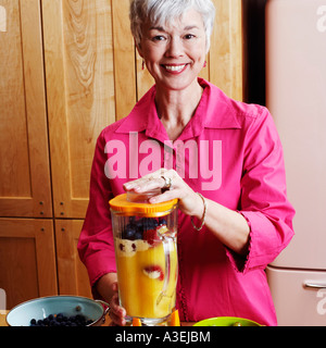 Portrait einer älteren Frau Mango Shake in der Küche vorbereiten Stockfoto