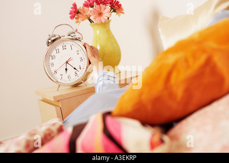 Zarte Frauenhand erreichen für einen Wecker Stockfoto