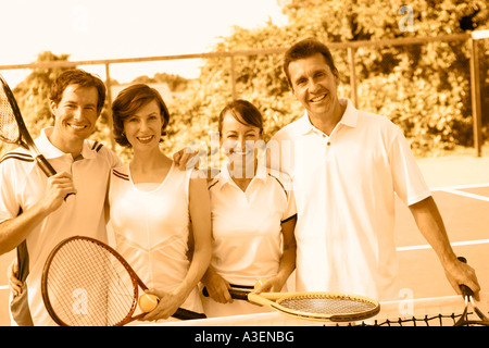 Porträt eines Mitte Erwachsenen Paares und ein älteres paar stehen zusammen auf einem Tennisplatz Stockfoto