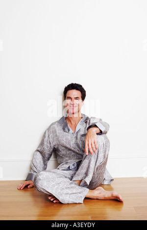 Porträt von einem reifen Mann mit seiner Hand auf sein Knie auf dem Boden sitzend Stockfoto