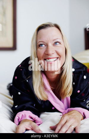 Nahaufnahme einer reifen Frau auf dem Bett liegend und lächelnd Stockfoto