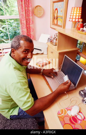 Porträt von einem reifen Mann hält eine Kreditkarte und einen Laptop verwenden Stockfoto