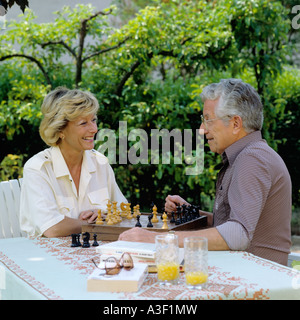 HERR ÄLTERES PAAR SPIELEN SCHACH IM GARTEN Stockfoto