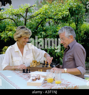 HERR ÄLTERES PAAR SPIELEN SCHACH IM GARTEN Stockfoto